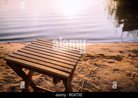 Kleine hölzerne Stuhl steht auf der Strand am Ufer des Sees. Stockfoto