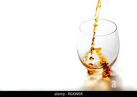 Gießt Whiskey aus Flasche in Glas ohne Eiswürfel auf weißer Tisch. Mit kopieren. Stockfoto