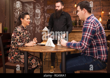 Kellner, das junge Paar mit Croissants. Im schönen Pub Datum. Stockfoto