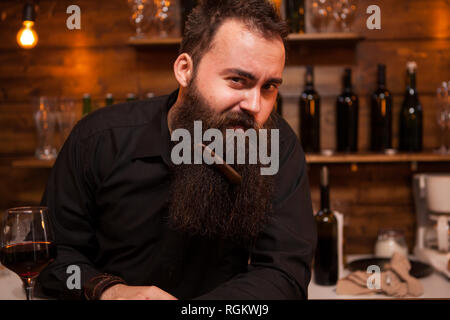 Hübscher junger Barkeeper spielen mit seinem Bart. Große Persönlichkeit. Stockfoto