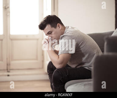 Portrait des jungen Mannes felling deprimiert und hoffnungslos allein weinend in Sofa home Leiden emotionalen Schmerz und Unglück. In den Leuten gebrochenes Herz, Bull Stockfoto