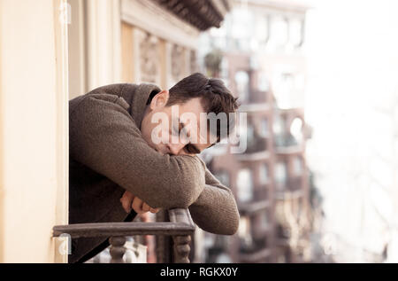 Traurig, unglücklich, deprimiert junger Mann weinen und suizidale Verzweiflung, isoliert und wertlos starrte hinunter die Straße home Balkon in Menschen Depres Stockfoto