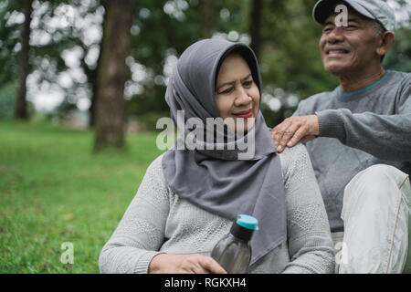 Alte Paar in einigen Massage während im Park sitzen Stockfoto
