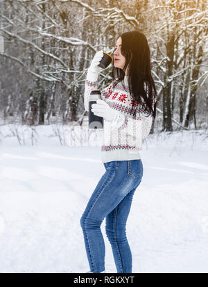 Das Mädchen Getränke bei einem heißen Getränk aus der Thermoskanne im Schnee Wald Stockfoto