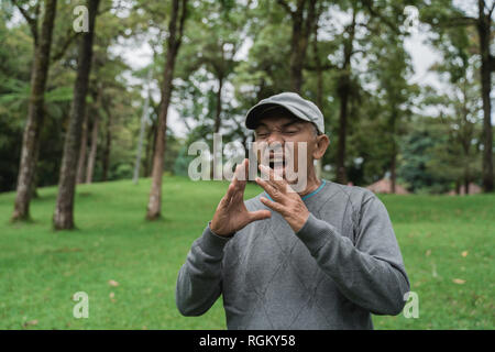 Alte asiatische Menschen niesen mit einer Grippe Stockfoto