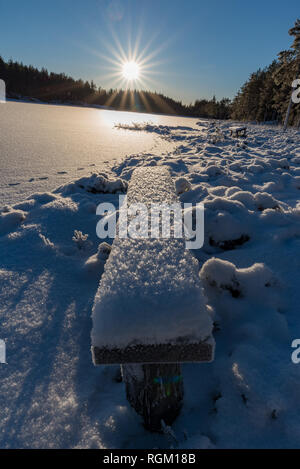 Sitzbank fallen im Schnee in der Nähe eines zugefrorenen See Stockfoto