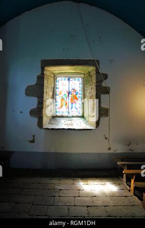 Sonnenlicht spähen durch ein Glasfenster in der historischen Kirche St. Cado Bretagne Frankreich Stockfoto