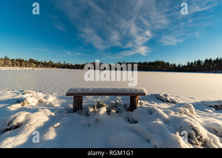 Sitzbank fallen im Schnee in der Nähe eines zugefrorenen See Stockfoto