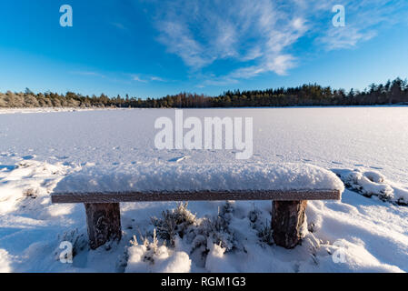 Sitzbank fallen im Schnee in der Nähe eines zugefrorenen See Stockfoto