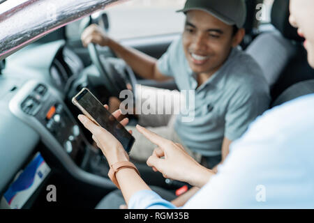 Porträt der Passagier sein Smartphone Anwendung angezeigt, um den Fahrer Stockfoto