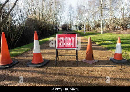 Einen Fußweg durch den Park ist geschlossen und ein Zeichen und orange Kegel blockieren den Weg. Stockfoto