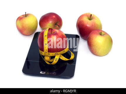 Große leckere Rote und gelbe reife Äpfel auf küchenwaage und gelbem Maßband auf weißem Hintergrund. Vorderansicht closeup Stockfoto