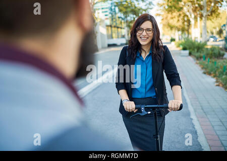 Smling Geschäftsfrau mit Scooter treffen Geschäftsmann Stockfoto