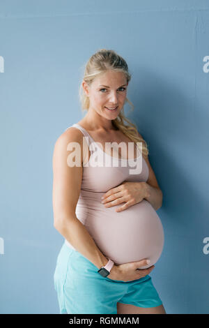 Portrait von lächelnden Schwangeren Frau, die auf der blauen Wand Stockfoto