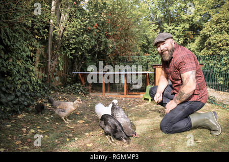 Mann in seinem eigenen Garten, mann Fütterung freie Hühner Stockfoto
