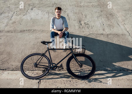 Junger Mann mit Pendler fixie Bike eine Pause sitzen auf Betonwand Stockfoto