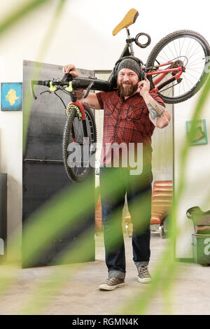 Portrait von lächelnden Mann mit Kopfhörern Fahrrad im Büro Stockfoto