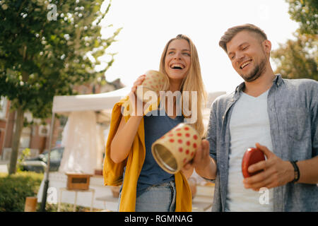 Belgien, Tongeren, glückliches junges Paar mit Blechdosen auf einem antiken Flohmarkt Stockfoto