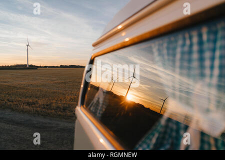 Wohnmobil in ländlichen Landschaft mit Windräder im Sonnenuntergang Stockfoto