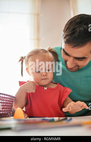 Portrait von kleinen Mädchen zeichnen mit Farbstiften, während ihr Vater sie beobachten Stockfoto