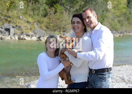 Glückliche Familie mit einem Hund an der Isar, Oberbayern, Deutschland Stockfoto