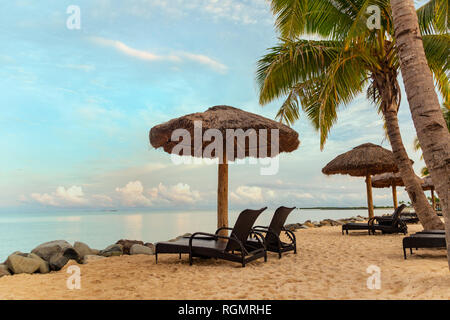 Zen Szene von Liegestühlen am Strand mit strohgedeckten Sonnenschirmen und ruhigen Ozean in Fidschi Stockfoto