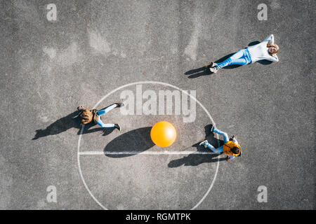 Österreich, Antenne, Ansicht von Basketball Feld mit großen Ball, die Mutter liegt auf dem Boden, Kinder sitzen Stockfoto