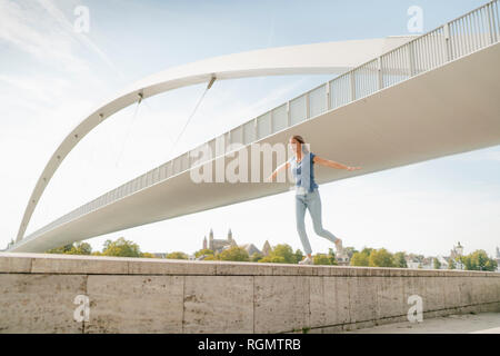 Niederlande, Maastricht, junge Frau, die auf eine Wand an einer Brücke Stockfoto