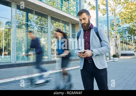 Geschäftsmann mit Mobiltelefon mit pendler Reiten auf Motorroller Stockfoto