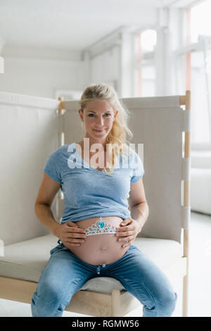 Portrait von lächelnden schwangere Frau tiara an ihrem Bauch gedrückt halten Stockfoto