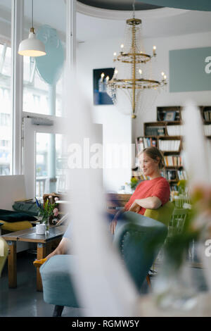 Lächelnde junge Frau in einem Cafe sitzen Stockfoto