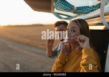 Paar Zähneputzen am Wohnmobil in ländlichen Landschaft bei Sonnenuntergang Stockfoto