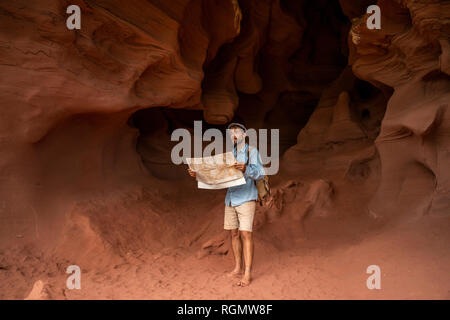 Junge Mann in einer Höhle, auf Karte suchen Stockfoto