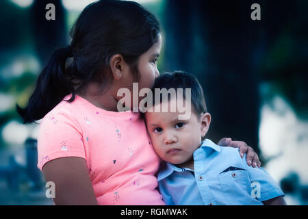 Eine emotional verletzte Junge lehnte sich auf ihre ältere Schwester und durch ihren Kuss und Support getröstet. Stockfoto