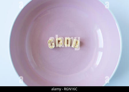 Das Wort 'gut' besteht aus echten pasta Buchstaben in einem rosa Schale. Stockfoto