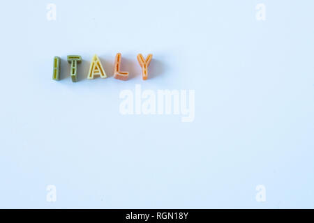 Das Wort "Italien" besteht aus echten pasta Buchstaben in die italienische Flagge Farben auf eine weiße Fläche. Hintergrund mit Kopie Raum auf der rechten Seite. Stockfoto