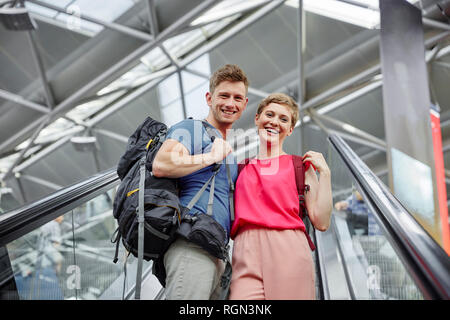 Glückliches Paar auf der Rolltreppe am Flughafen Stockfoto