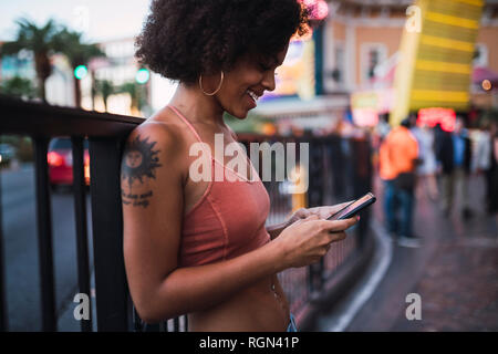 USA, Nevada, Las Vegas, glückliche junge Frau mit Handy in der Stadt Stockfoto