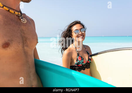 Junges Paar am Strand, Surfbretter, lächelnde Frau Stockfoto