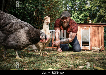 Mann in seinem eigenen Garten, mann Fütterung freie Hühner Stockfoto