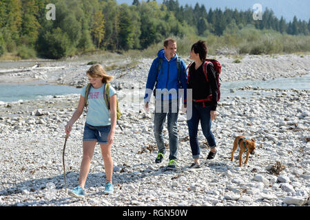 Familie wandern mit Rucksack und einem Hund an der Isar, Oberbayern, Deutschland Stockfoto