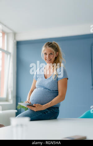 Portrait von lächelnden schwangere Frau mit Tablet Stockfoto