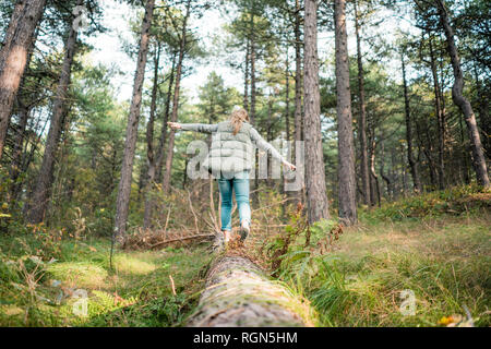 Kleines Mädchen Balancieren auf einem Baumstamm im Wald Stockfoto