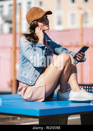 Entspannt junge Frau sitzt auf Tischtennis Musik hören Stockfoto