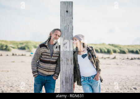 Reifes Paar am Strand, lehnte sich auf Holz Pol Stockfoto