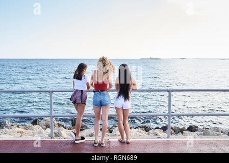 Spanien, Mallorca, Palma, Rückansicht von drei jungen Frauen am Meer stehend Stockfoto