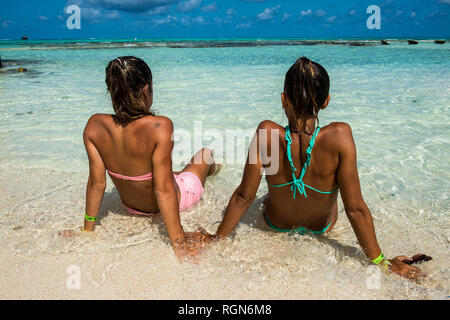 Karibik, Kolumbien, San Andres, El Acuario, Ansicht der Rückseite von zwei Frauen in seichtem Wasser sitzen Stockfoto