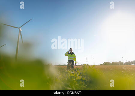 Ingenieur steht ein Feld an einem Windpark Gespräch am Handy Stockfoto