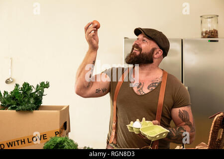 Reifer Mann mit Lieferservice Kontrolle Eier, bevor Sie die Verpackung in Kartons Stockfoto