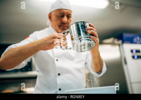 Bäcker arbeiten mit Mehl Sichter in Bäckerei Stockfoto